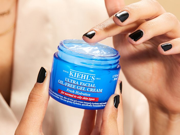 Close-up picture of a person with short black nails holding the Kiehl’s Ultra Facial Oil-Free Gel Cream