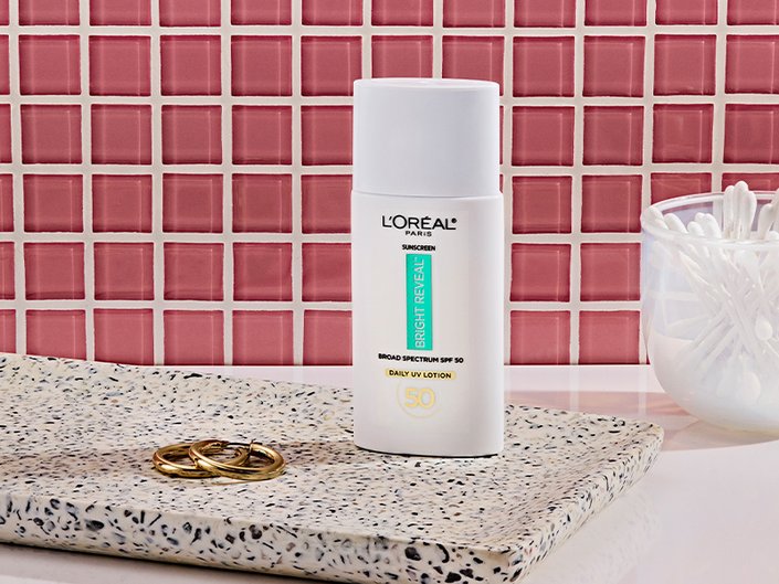 loreal paris bright reveal sunscreen photographed in front of a pink tile background