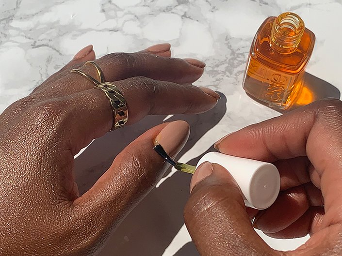Picture of a person applying cuticle oil to their thumb