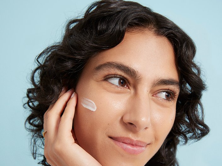 person with dark hair and retinol on their face